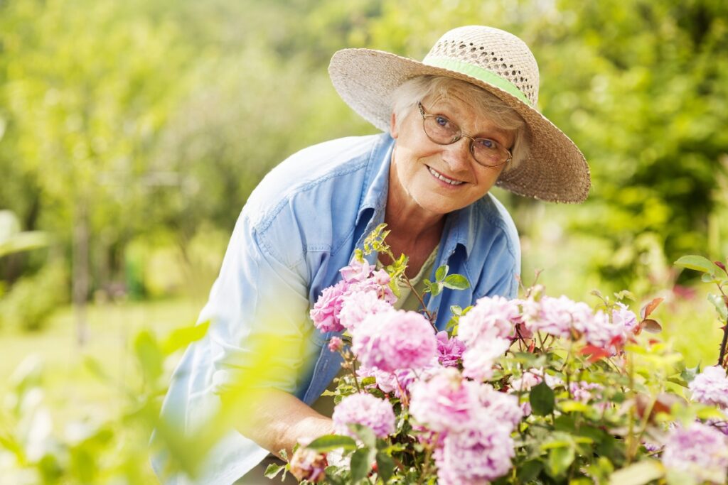 Starší žena pečující o květiny na zahradě.